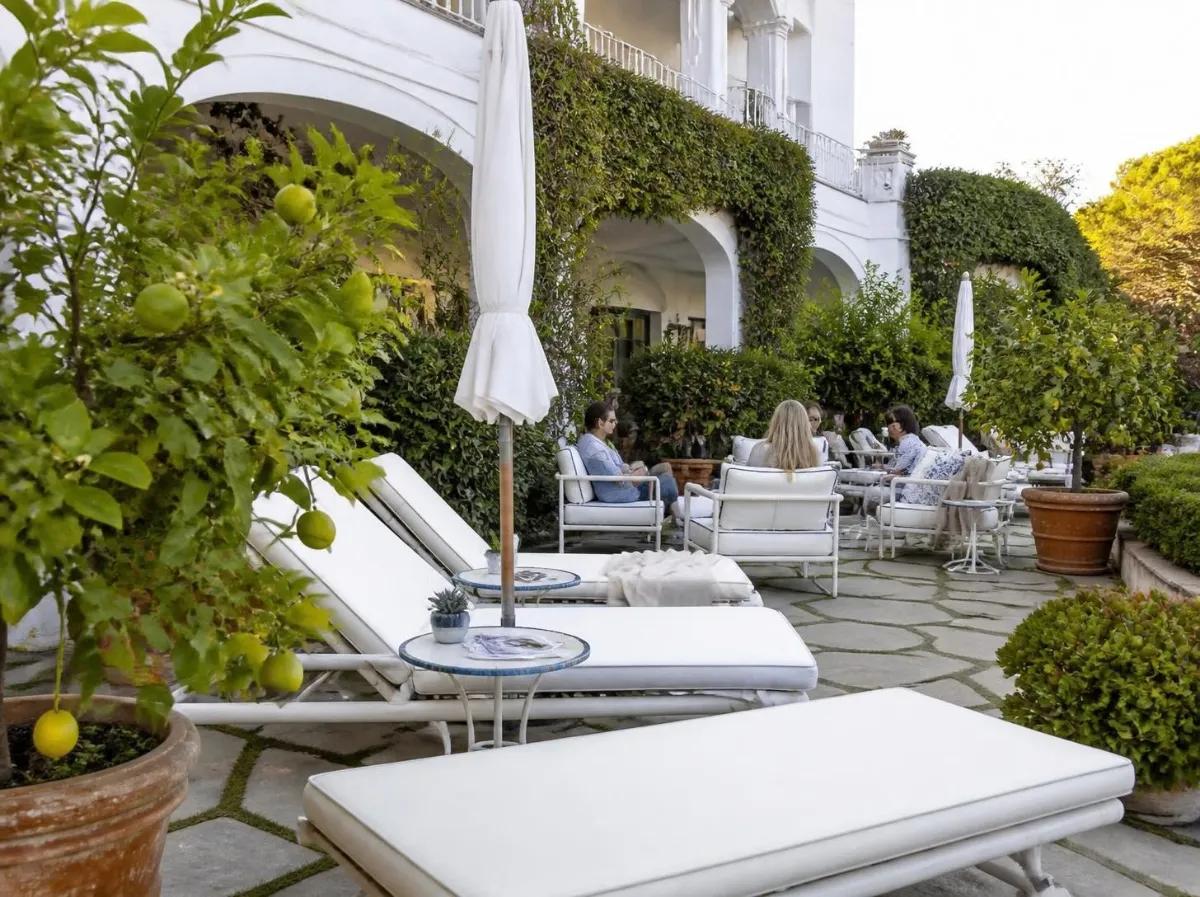 Terrazza giardino di un hotel con lettini, siepi e limoni in vaso