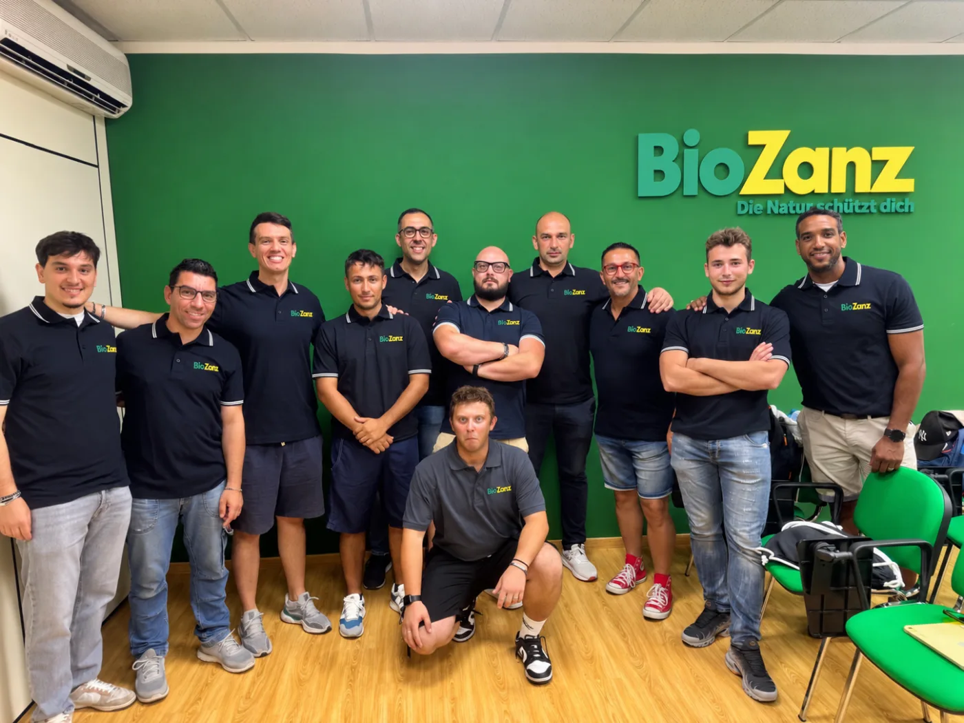 Il team BioZanz in sede, davanti alla parete verde con il logo